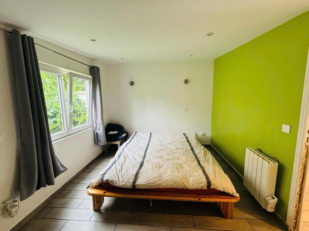 a bedroom with a bed with a green wall at Studio T2 proche Jardin de Plantes Rouen in Rouen