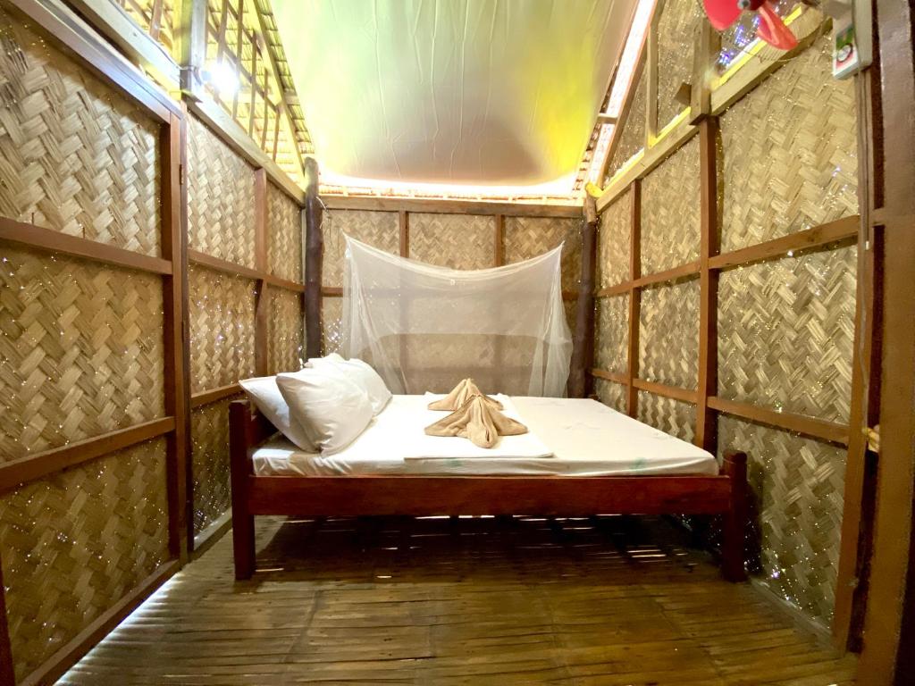 a small bed in a wooden room with a window at Ocam Ocam Casadyan Inn in New Busuanga