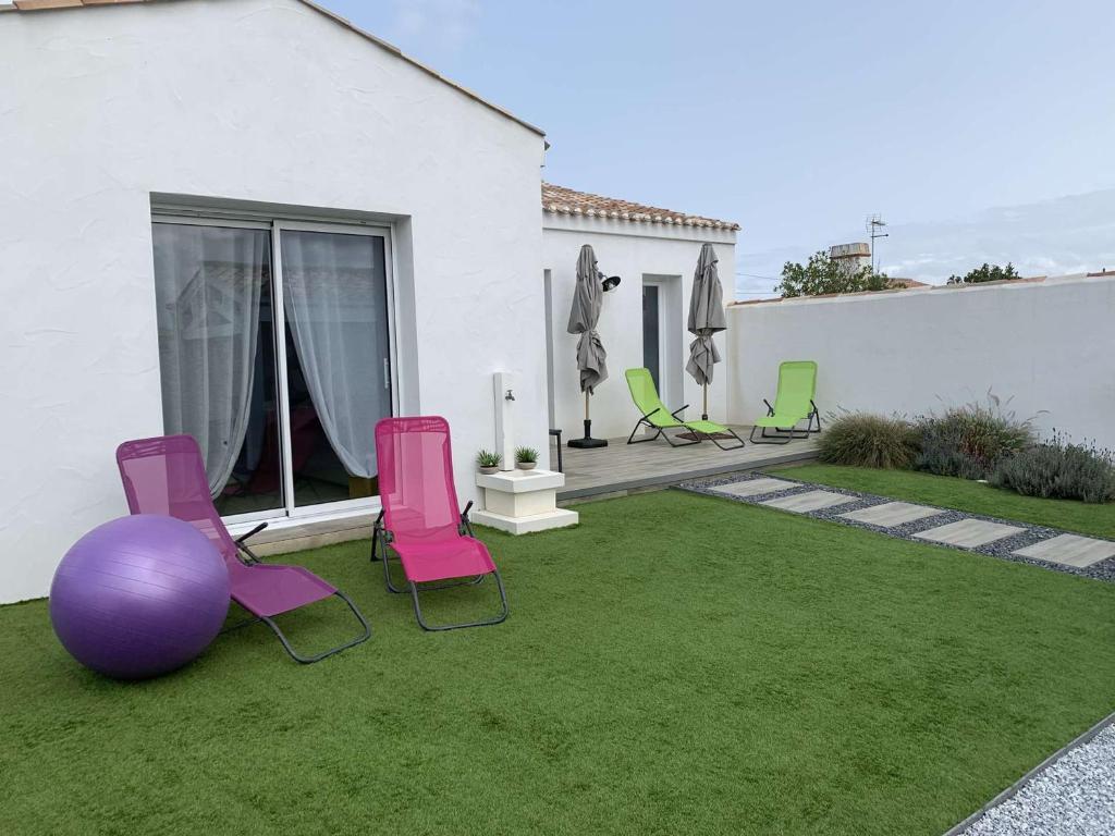 une cour avec des chaises roses et une boule violette dans l'établissement Maison de vacances avec jardin clos, à proximité de la plage de Barbâtre, 6 couchages - FR-1-224B-227, à Barbâtre
