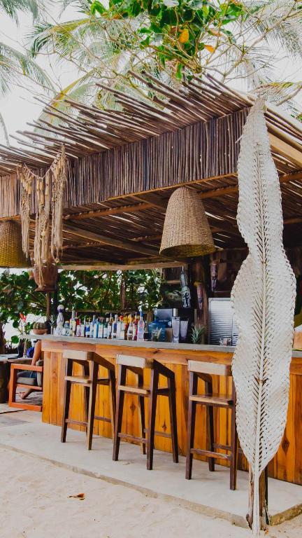 a bar with tables and stools under a straw umbrella at Casa Coraje in Palomino