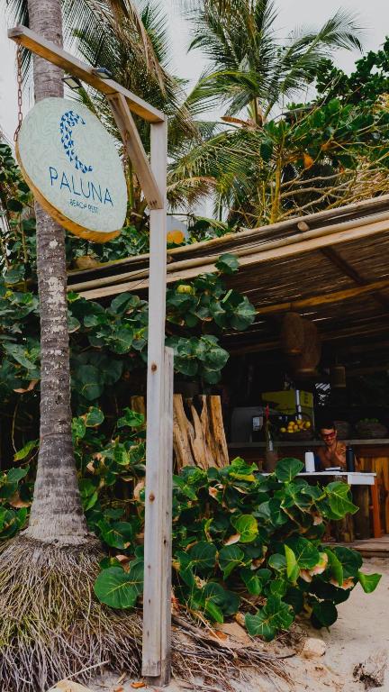 a sign for a restaurant in front of a palm tree at Casa Coraje in Palomino