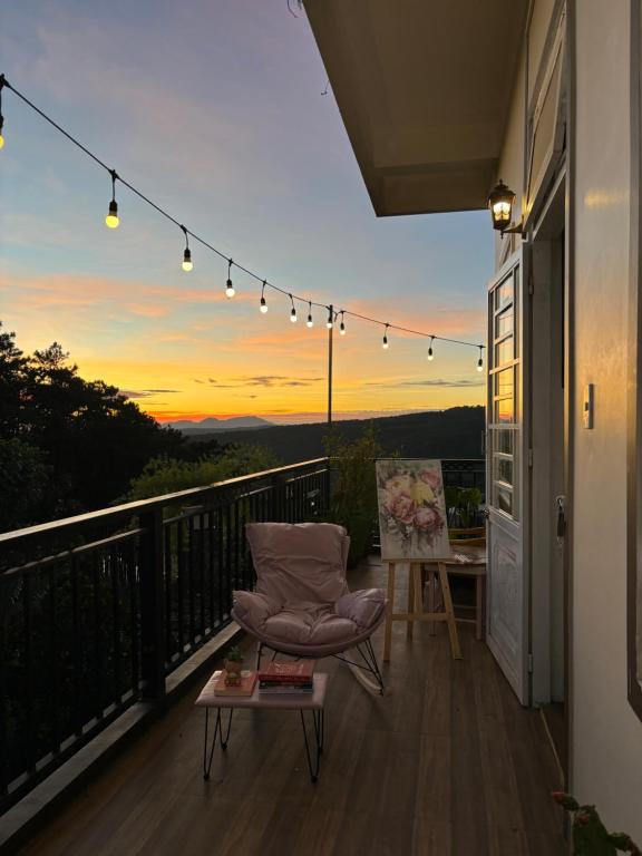 a balcony with a chair and a sunset at Ghé nhà mình Homestay in Ấp Trạm Hành