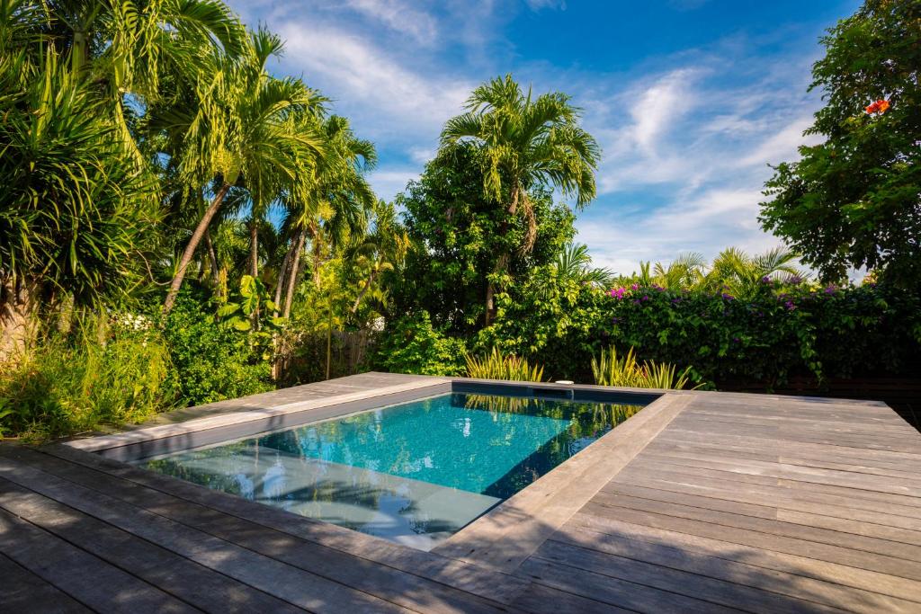 a swimming pool in a garden with a wooden deck at Villa Le Ropert'Zen in Saint-François