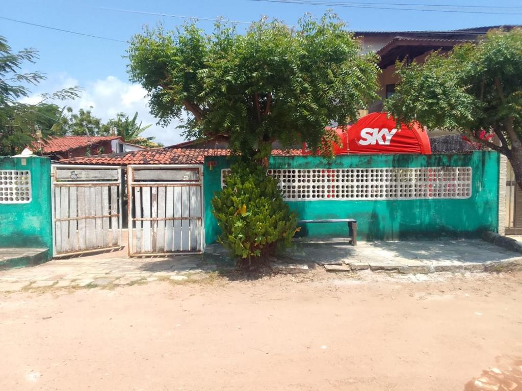 a green fence with a tree and a bench at Flor de cacto in Cabedelo