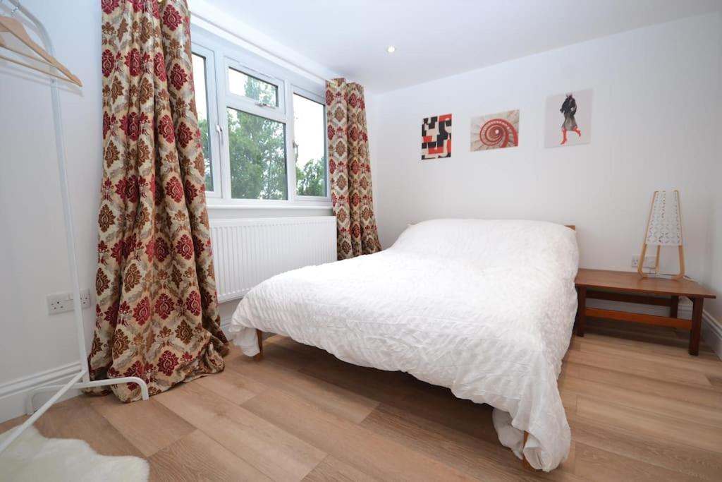 Worcester ParkにあるFreshly refurbished, peaceful Victorian houseの白いベッドと窓のある寝室