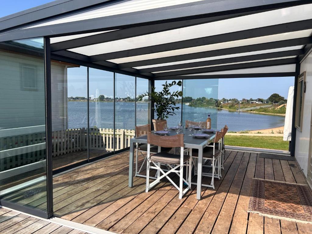 patio ze stołem i krzesłami na pokładzie w obiekcie Luxe chalet direct aan het water met strand w mieście Lith