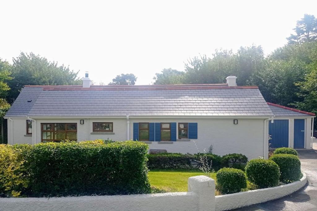a white house with a roof and some bushes at Cherrymount Cottage in Newcastle