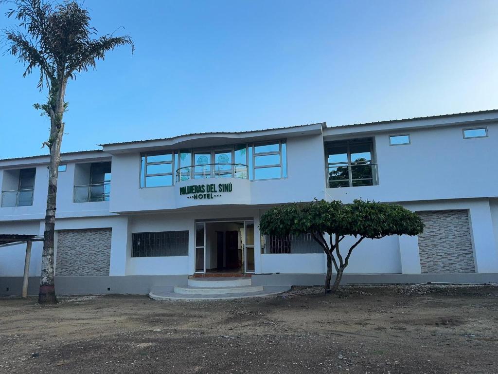 a white building with a palm tree in front of it at Hotel Palmeras Del Sinu in Lorica