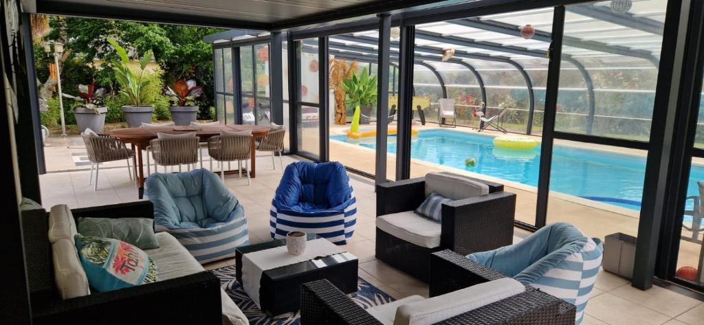 a conservatory with chairs and a table and a pool at Fare-Kermenezy maison avec piscine chauffée in Locmaria-Grand-Champ