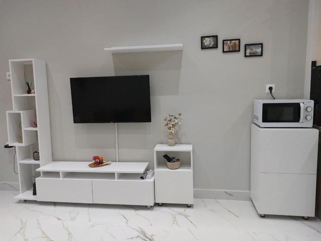 a white living room with a tv and a refrigerator at Loutraki comfortable apartment center 50m from the sea in Loutraki