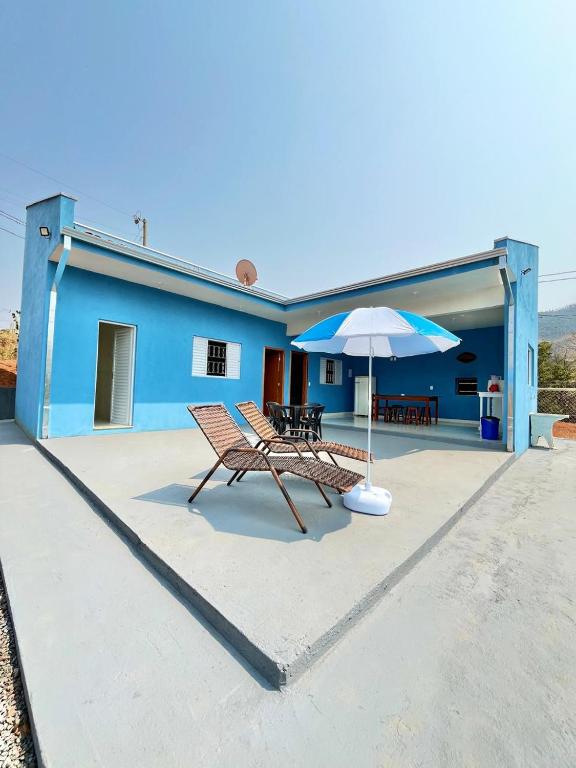 a blue house with a bench and an umbrella at Chácara Primavera in Monte Sião