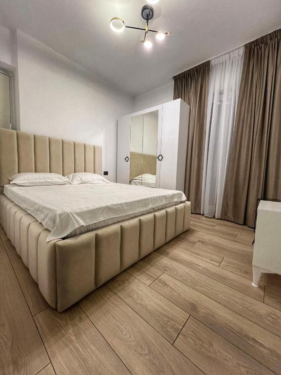a bedroom with a large bed and a wooden floor at Vily Apartment in Focşani
