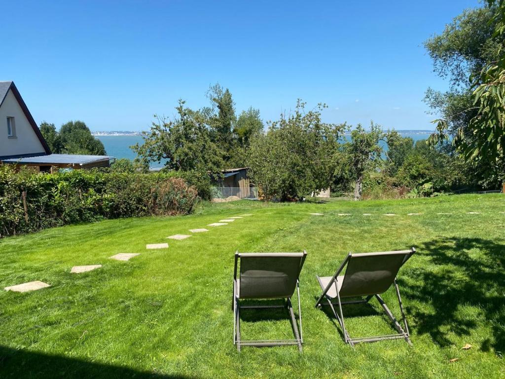 two chairs sitting in the grass in a yard at Gites de la Baie d'Honfleur in Cricquebœuf