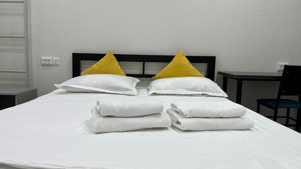 a white bed with towels on it with yellow pillows at Апартамент в центре города Классик in Bishkek