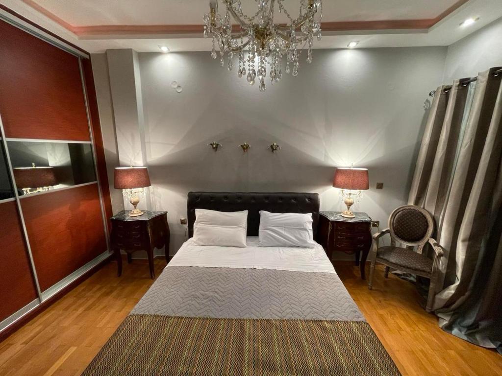 a bedroom with a bed and two tables and a chandelier at Balcony With A View in Nafplio