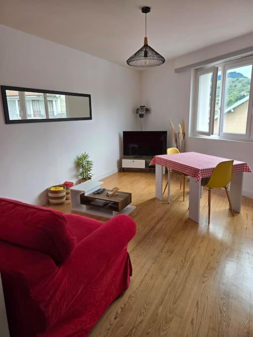 un salon avec un canapé rouge et une table dans l'établissement Appartement vue sur château fort de Lourdes, à Lourdes