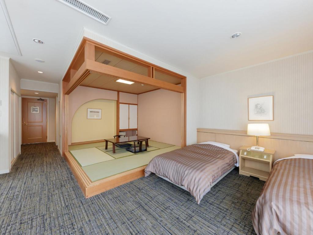 une chambre d'hôtel avec deux lits et une table dans l'établissement Hotel New Momiji, à Nasushiobara 19 autres photos