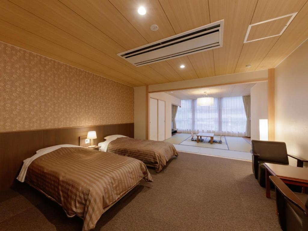 une chambre d'hôtel avec deux lits et une fenêtre dans l'établissement Hotel New Momiji, à Nasushiobara