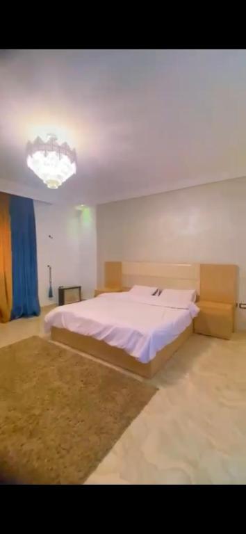 a bedroom with a large bed and a chandelier at شقة فيلا دبلوكس رائعة ومفروشة مدينة اكتوبر مصر in Sheikh Zayed
