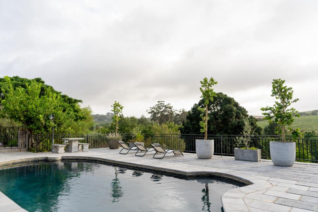 a swimming pool with chairs and a fence at Avemore Orchard Apartment - with full Backup power in Stellenbosch