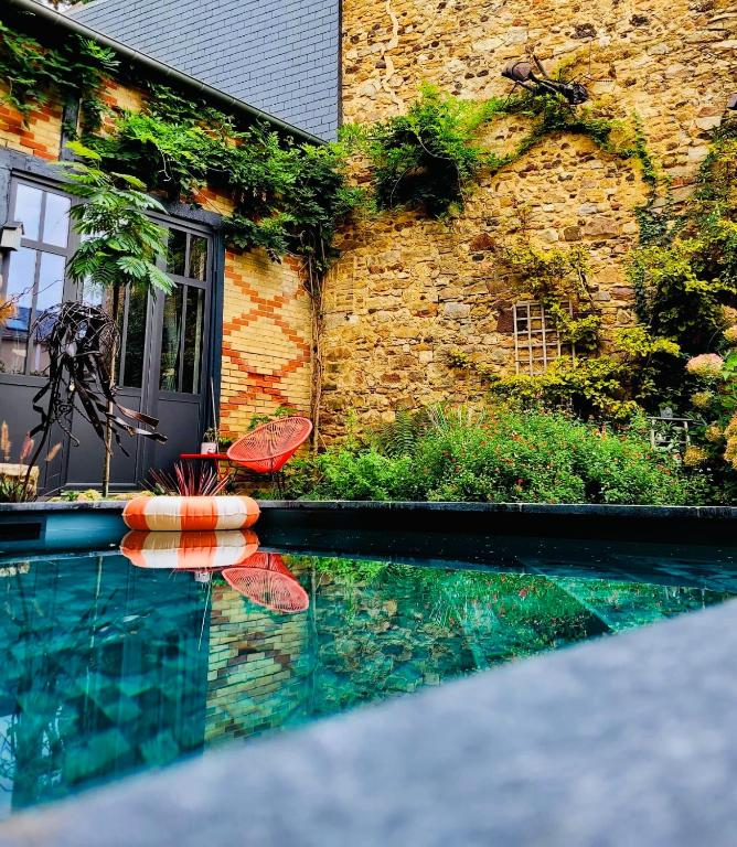 une piscine avec deux chaises et un bâtiment dans l'établissement L'Atelier Planqué, au Mans