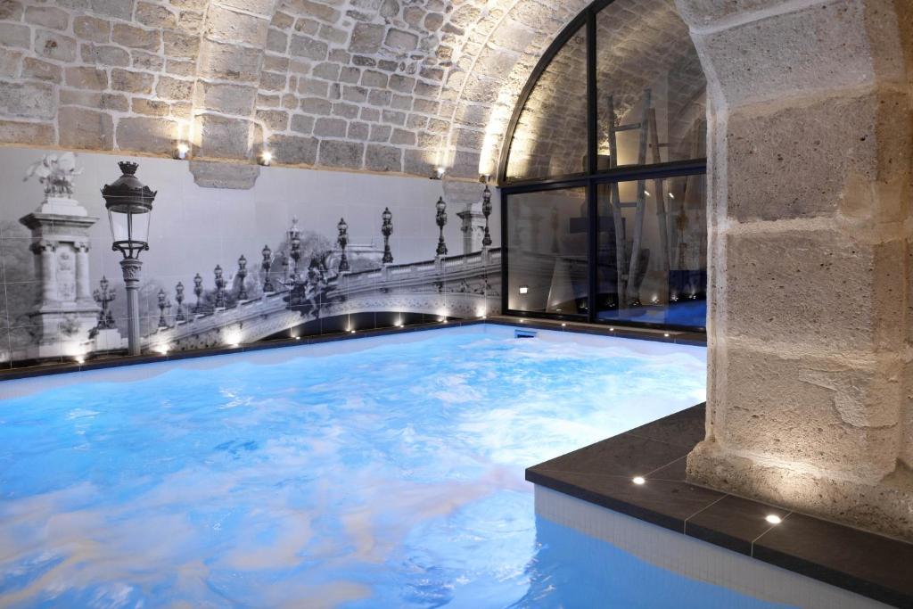 une grande piscine d'eau dans un bâtiment dans l'établissement Hotel La Lanterne & Spa, à Paris