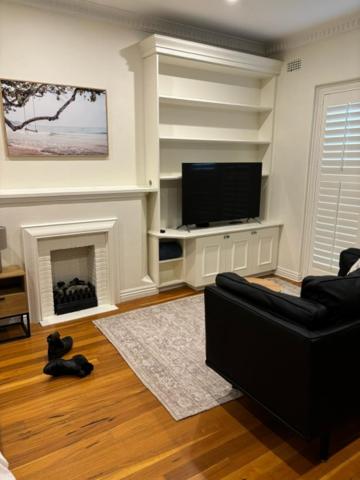 a living room with a black couch and a flat screen tv at Regents Gate East Melbourne in Melbourne