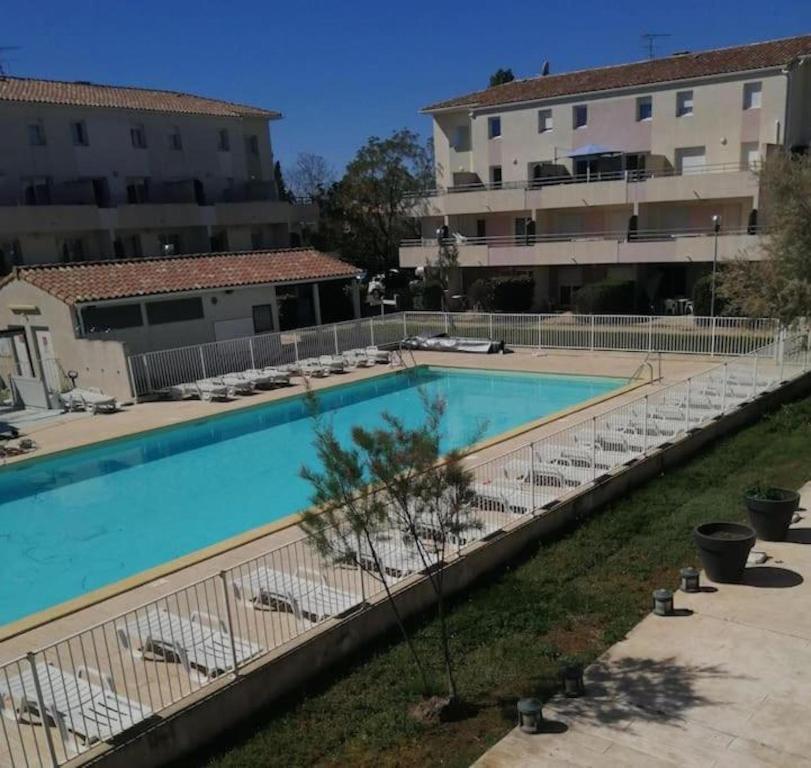 une grande piscine avec des chaises et un bâtiment dans l'établissement Joli 2 pièces cosy, au Grau-du-Roi