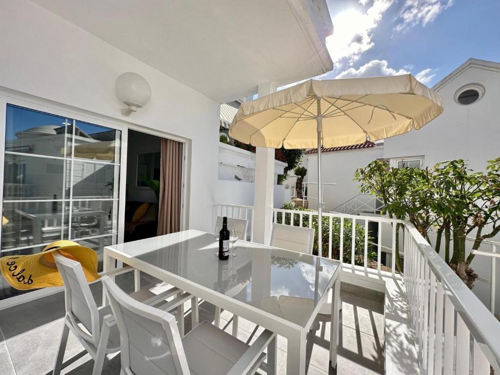 a white table with chairs and an umbrella on a balcony at Luxury Apartment Tenerife in Adeje