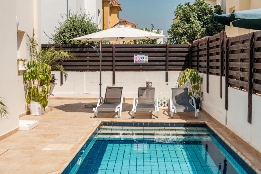 a swimming pool with two chairs and an umbrella at Mermaid Villa 16 in Ayia Napa