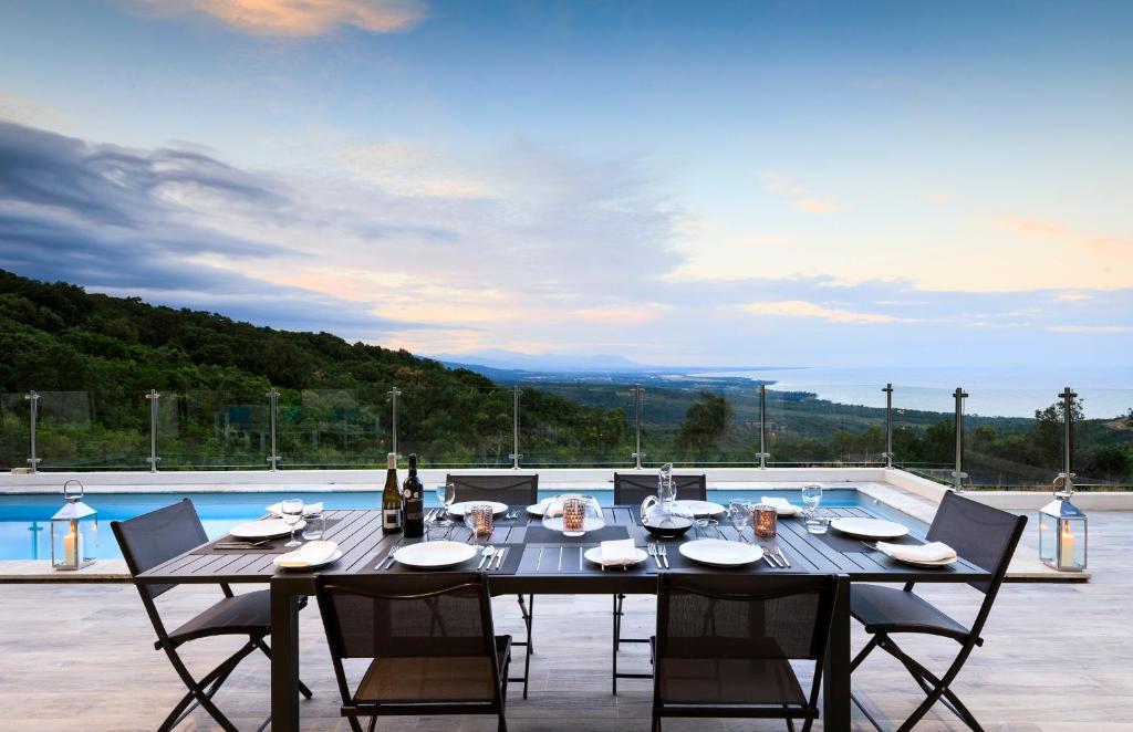 - une table à manger et des chaises sur une terrasse avec piscine dans l'établissement a STELLA DI FOCE, à Kamiesch