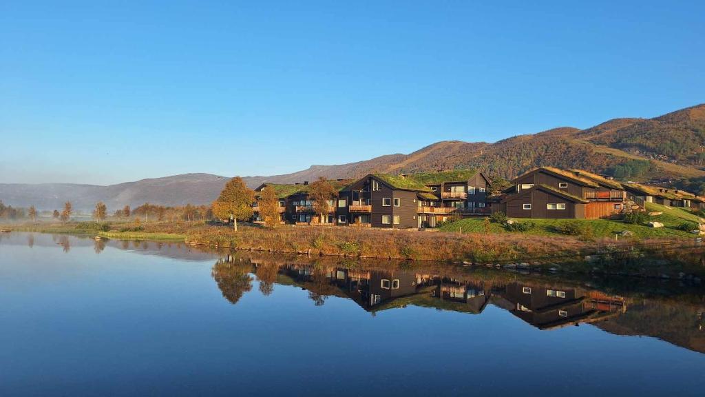 a reflection of houses in the water with mountains at Sentral leilighet på Geilo in Geilo