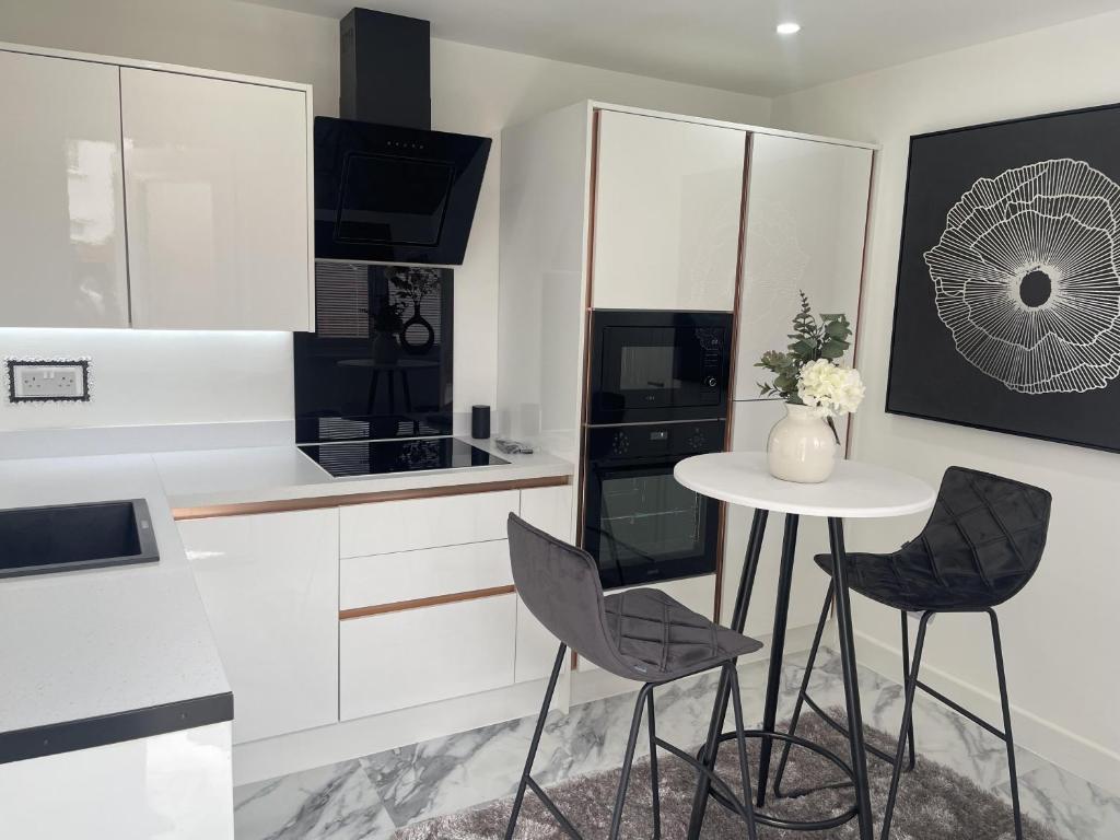 a white kitchen with a table and chairs at Modern-luxury 1bedroom-EnsuiteBathroom-Garden-Wifi in Basildon
