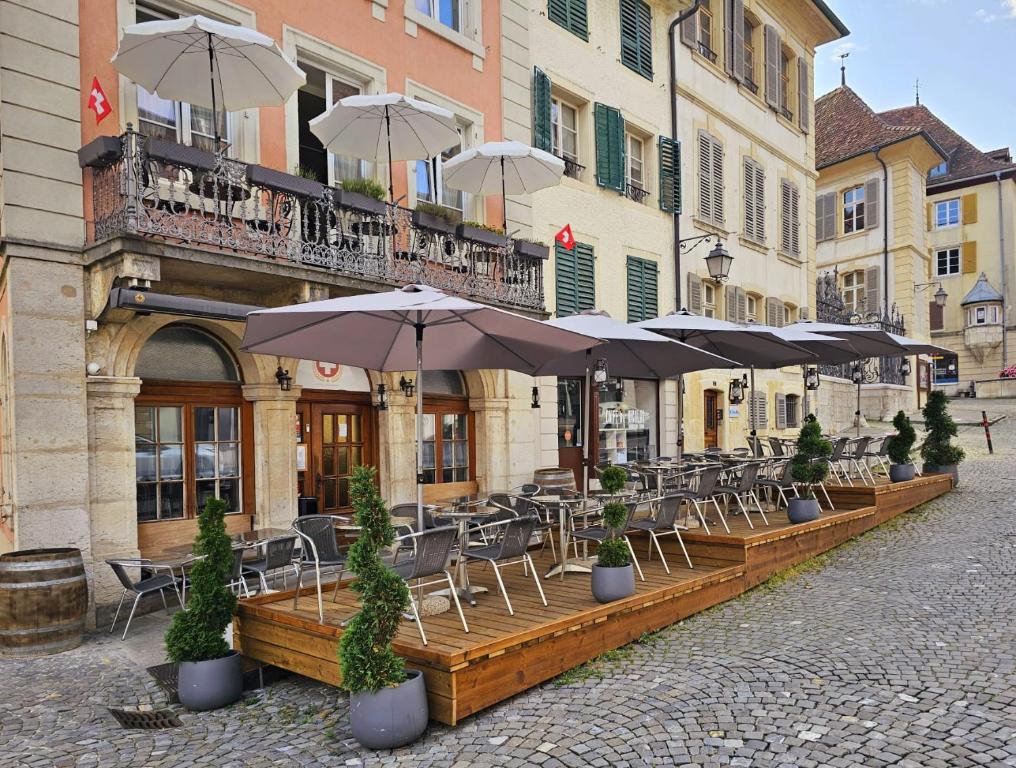 a row of tables with umbrellas in front of a building at La Croix Fédérale in Porrentruy