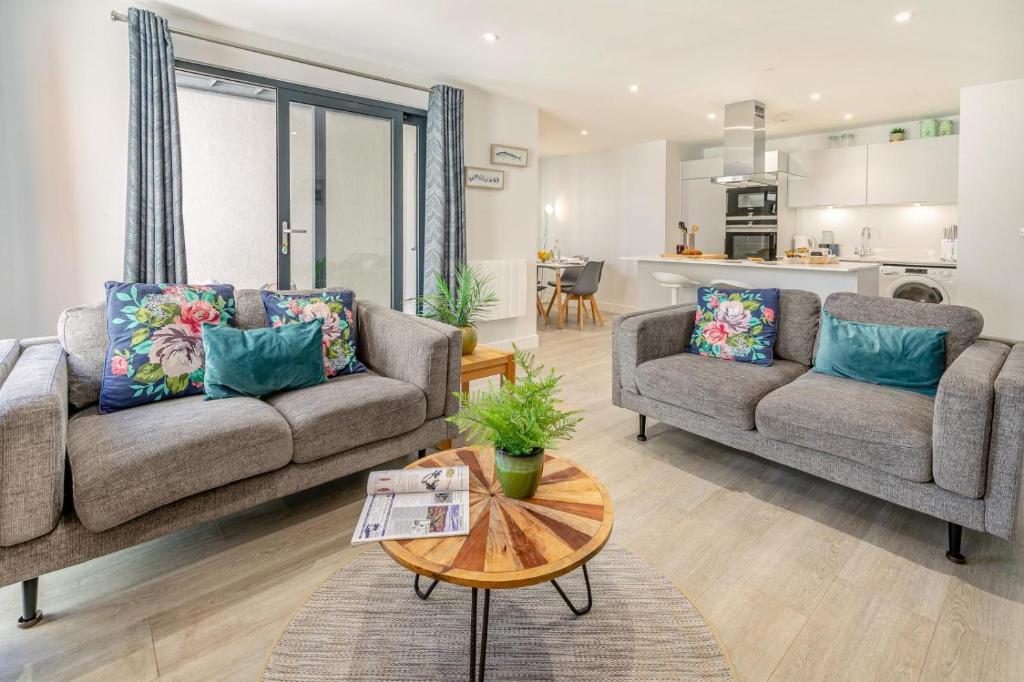 a living room with two couches and a table at 6 Putsborough - Luxury Apartment at Byron Woolacombe, only 4 minute walk to Woolacombe Beach! in Woolacombe
