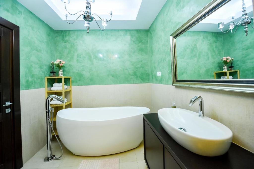 une salle de bain avec une grande baignoire et un miroir dans l'établissement Luxury Apartment, à Braşov