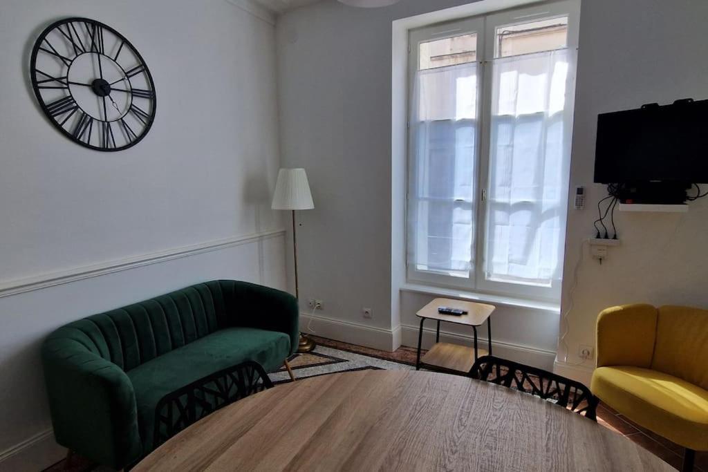 un salon avec un canapé et une horloge au mur dans l'établissement Maison de ville Auxerroise, à Auxerre