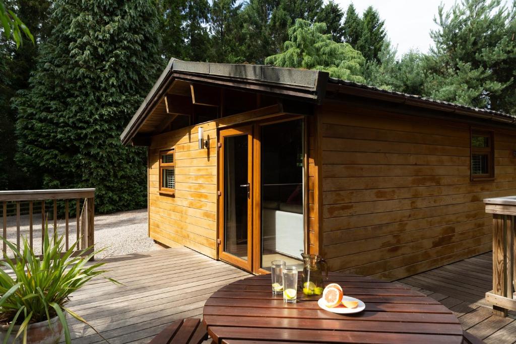 a small wooden cabin with a table on a deck at Wensleydale Lodges in Masham