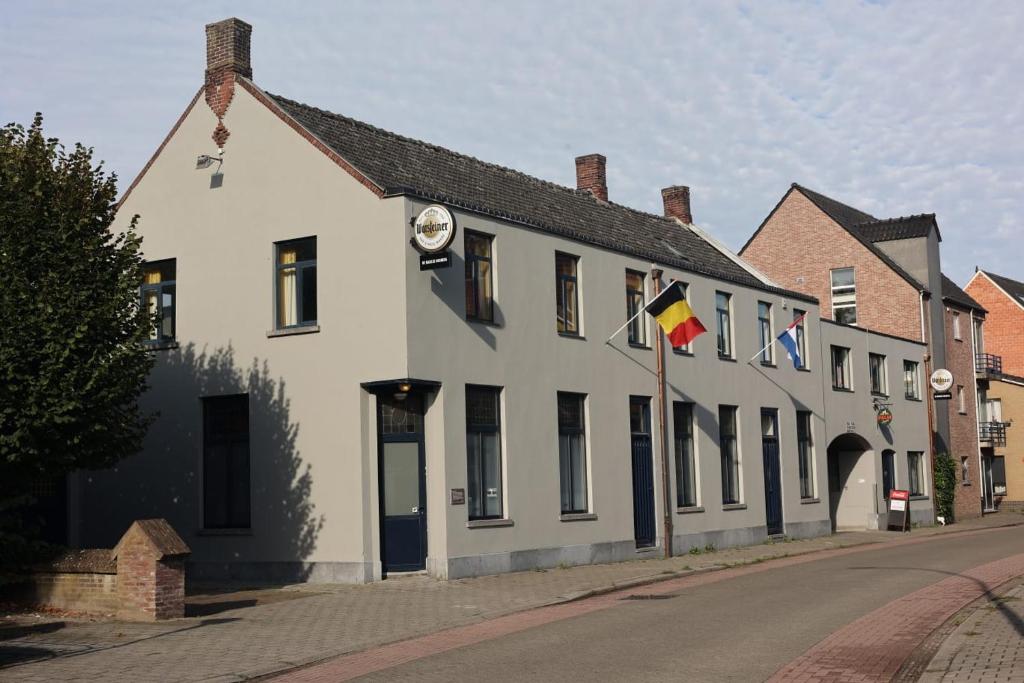 a row of white buildings with flags on a street at De Baolse Herberg in Baarle-Hertog