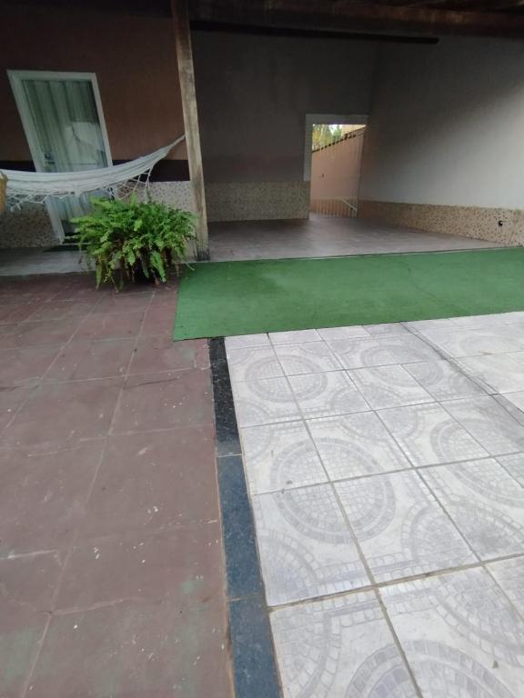 a patio with a green floor and a hammock at Casa na Praia in Jacaraípe