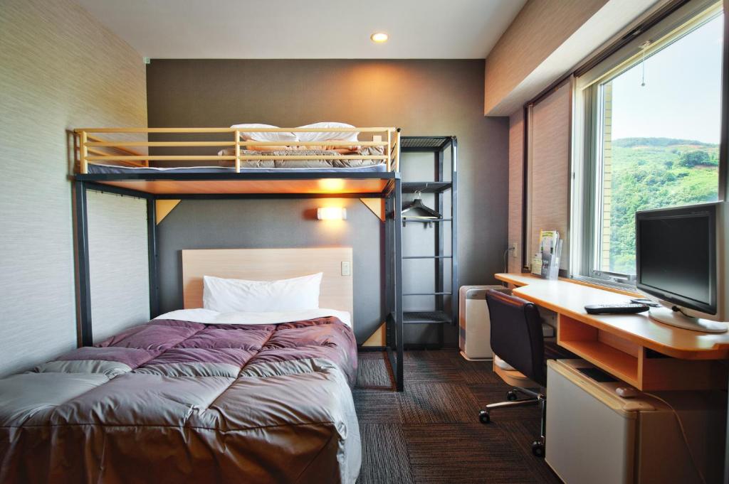 a bedroom with a bunk bed and a desk and a computer at Super Hotel Arai Niigata in Myoko