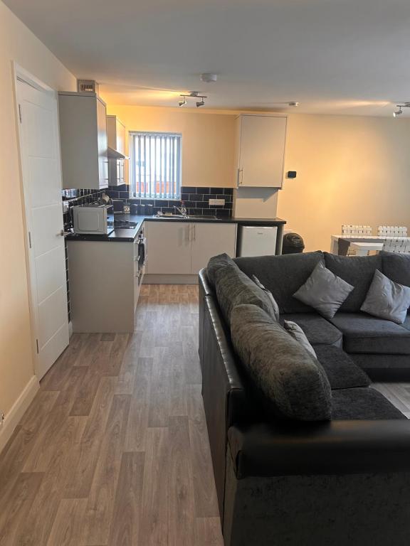 a living room with a couch and a kitchen at Brand new apartments with Open plan kitchens & Diner , FREE WIFI & NETFLIX included in Burton upon Trent