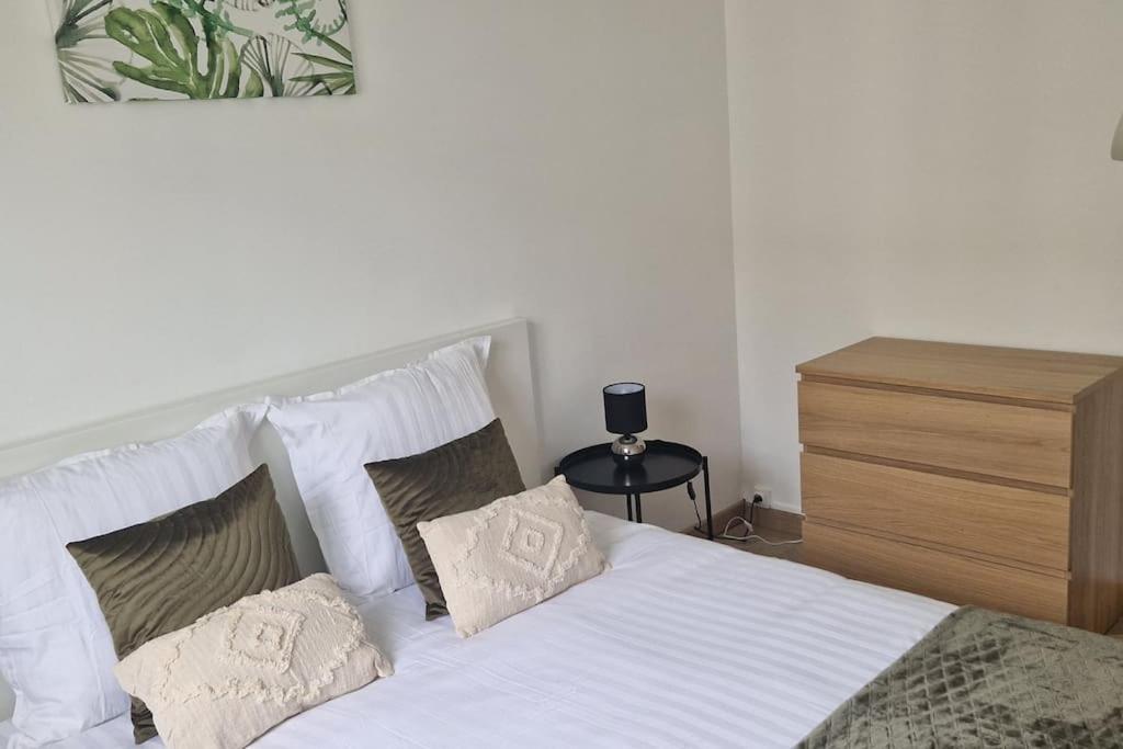 une chambre avec un lit avec des draps blancs et des oreillers dans l'établissement La Belle Vue d'Auxerre, à Auxerre