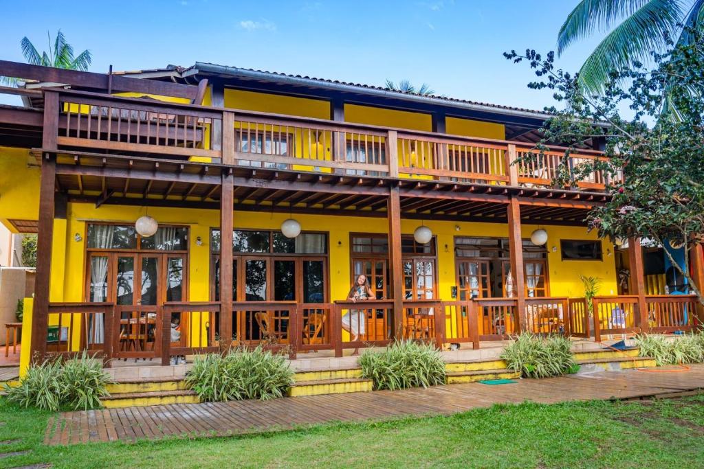 a yellow house with a large deck on it at Flats Theo Peleteiro Praia da concha Flatitacareconcha in Itacaré