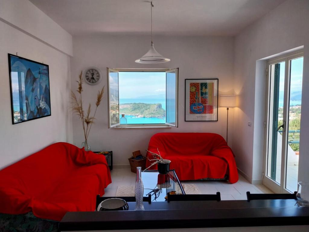 Una sala de estar con un sofá rojo y una ventana. en Casa Re di Picche, en San Nicola Arcella