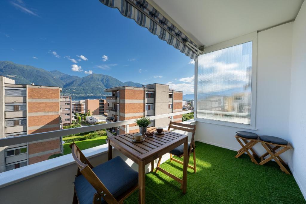 ein Balkon mit Tisch und Stühlen und einem großen Fenster in der Unterkunft Renovated Lake View Apt with AirCon in Minusio