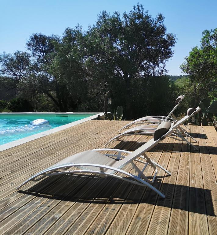 2 chaises longues assises sur une terrasse à côté d'une piscine dans l'établissement U caseddu di Monacia, à Monacia-dʼAullène