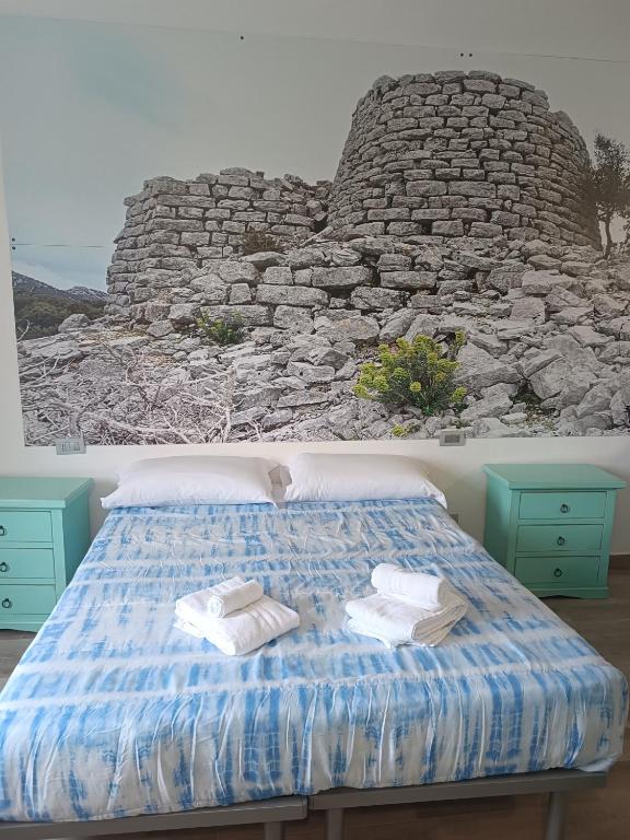 a bed with towels on it with a stone wall at bed and breakfast Murales Orgosolo in Orgosolo