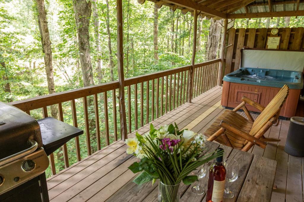 a porch of a cabin with a table and flowers at Creekside Cabin Hot Tub Near Wineries Sleeps 4 in Dahlonega