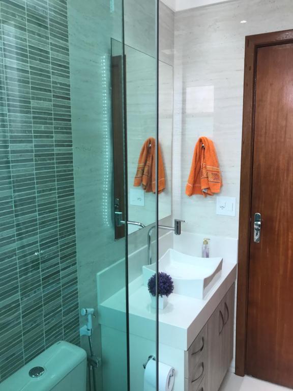Un baño con dos lavabos y una ducha de cristal. en Apartamento Charme Cabo Frio RJ, en Cabo Frío